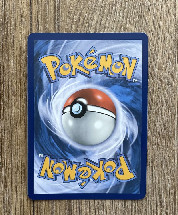 The back of a genuine modern Pokémon card showing the blue swirl background and Poké Ball artwork